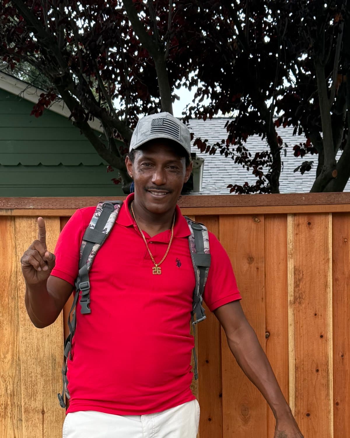 Deonte smiling in a red polo and a gray cap